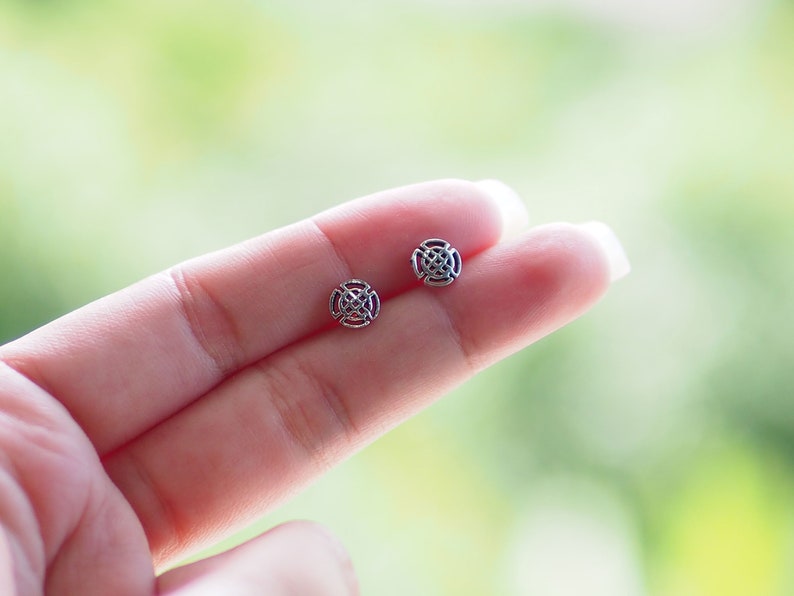 K&ouml;nnte beinhalten: Ein Paar silberne Ohrringe mit einem runden, filigranen Design. Die Ohrringe sind klein und zart.