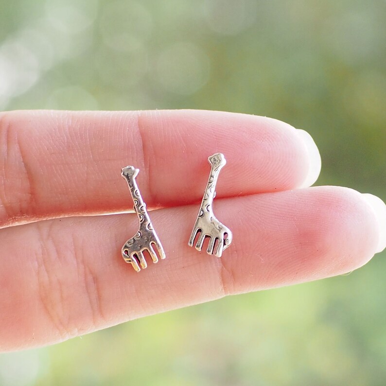 Puede incluir: Un par de pendientes de plata con forma de jirafa. Las jirafas est&aacute;n detalladas con un patr&oacute;n de manchas.
