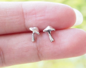 May include: A pair of silver mushroom stud earrings. The earrings are small and delicate, and they feature a realistic mushroom design.