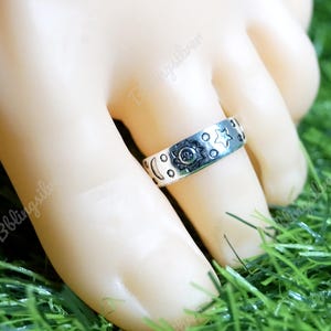 May include: A silver ring featuring a design of moons, stars, and a sun on a finger.