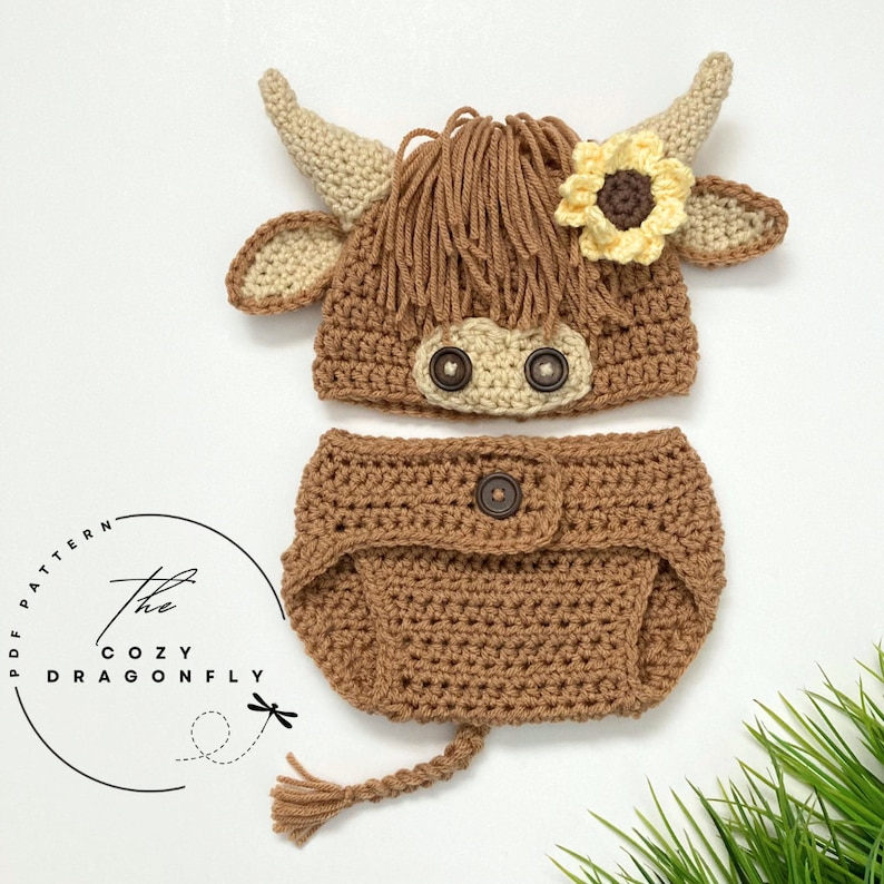 May include: A crocheted brown and cream highland cow costume for a baby. The costume includes a hat with a flower and a diaper cover with a tail.