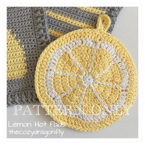 May include: A crochet lemon hot pad in yellow and white. The hot pad is shaped like a slice of lemon with a white center and yellow edges. The text "PATTERN ONLY Lemon Hot Pads thecozydragonfly" is visible in the image.