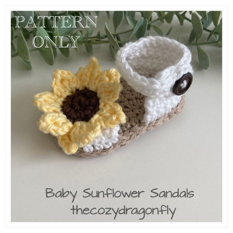 K&ouml;nnte beinhalten: H&auml;kelmuster f&uuml;r Babysandalen mit Sonnenblume. Die Sandalen sind wei&szlig; und braun mit einer gelben Sonnenblume auf der Vorderseite. Das Muster ist zum Download verf&uuml;gbar.