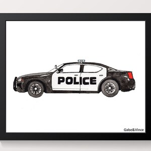 May include: A framed watercolour print of a black and white police car. The word "POLICE" is displayed on the side. The artwork is set against a white background and framed in black. The artist's name, "Gabe&Vince", is in the bottom right corner.