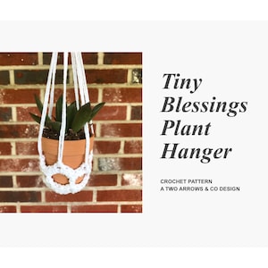 May include: White crocheted plant hanger with a small potted plant hanging from it against a red brick wall. The text "Tiny Blessings Plant Hanger" is written in black text below the image. The text "Crochet Pattern A Two Arrows & Co Design" is written in smaller black text below the title.