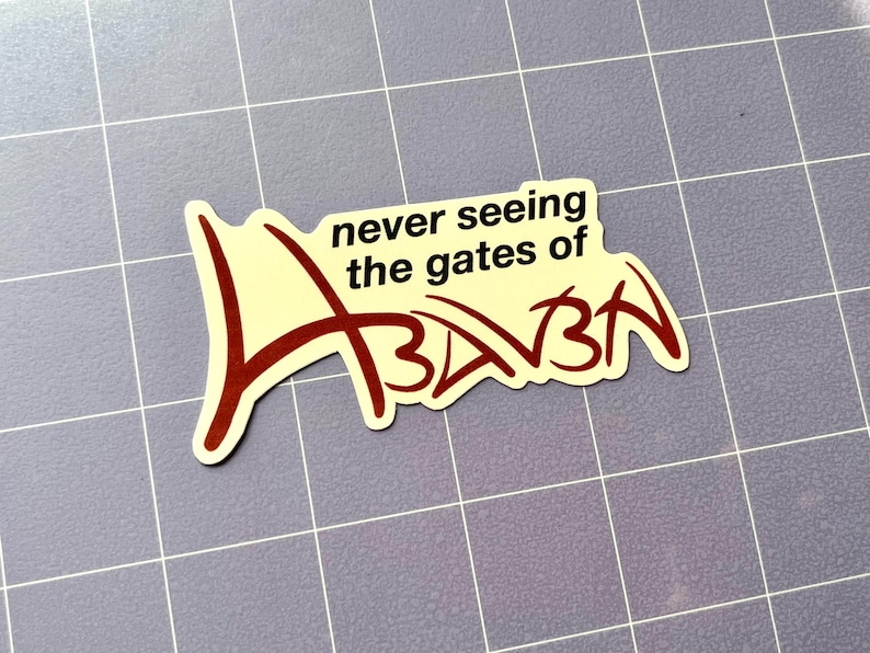 Puede incluir: Una pegatina con el texto "never seeing the gates of Azkaban" en una fuente estilizada. La pegatina tiene un fondo color crema con letras rojo oscuro y un contorno negro. La pegatina est&aacute; sobre una superficie gris claro.