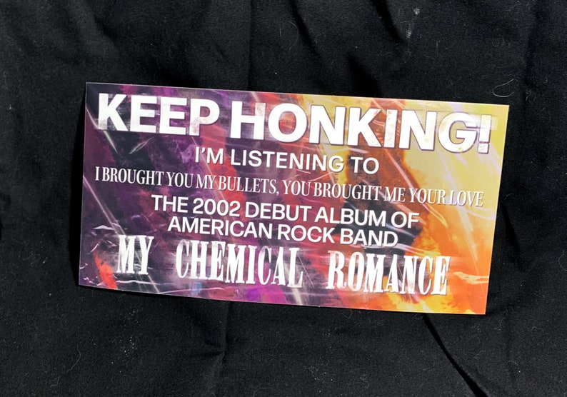 May include: Rectangular sticker with the text "KEEP HONKING!" and "I'M LISTENING TO" above the text "I BROUGHT YOU MY BULLETS, YOU BROUGHT ME YOUR LOVE". The sticker also says "THE 2002 DEBUT ALBUM OF AMERICAN ROCK BAND MY CHEMICAL ROMANCE".