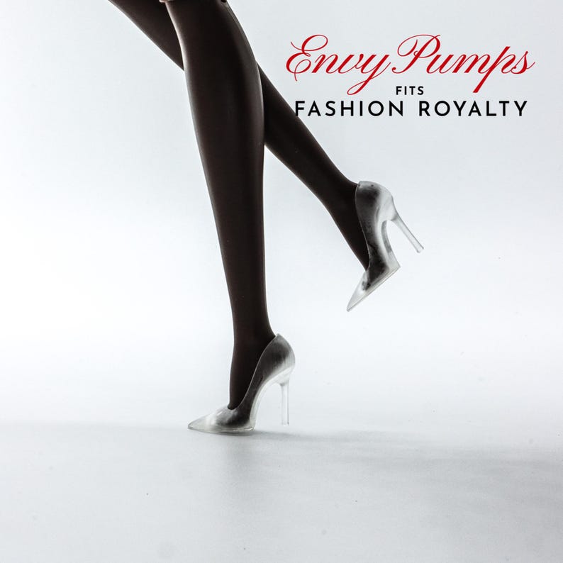 May include: A pair of silver high-heeled shoes with clear heels. The shoes are on a white background. The text "Envy Pumps FITS FASHION ROYALTY" is visible in the top right corner of the image.