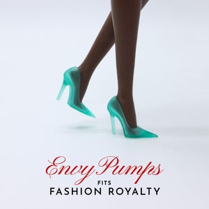 May include: A pair of teal blue high-heeled pumps with a pointed toe. The shoes are made of a translucent material and have a stiletto heel. The text "Envy Pumps FITS FASHION ROYALTY" is printed below the shoes.