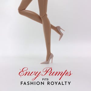 May include: A pair of nude-colored high heels with a stiletto heel. The shoes are called "Envy Pumps" and fit "Fashion Royalty" dolls.