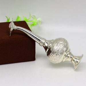 May include: A silver water sprinkler with intricate floral designs. The sprinkler has a long spout and a round base.