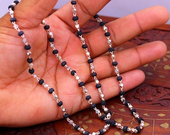 May include: A black and silver beaded necklace with alternating black beads and silver faceted beads.