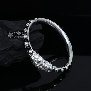 May include: A silver ring with black beads and a textured design. The ring is on a black background.
