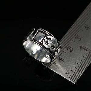 May include: Silver ring with an intricate design featuring a square shape and a floral pattern. The ring is marked with the number "925" indicating it is made of sterling silver.