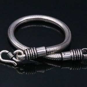 K&ouml;nnte beinhalten: Ein silbernes Schlangenkettenarmband mit einem Hakenverschluss. Das Armband ist etwa 19 cm lang.