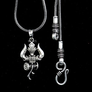 May include: A silver necklace with a pendant featuring a stylized depiction of a trident and a drum. The necklace has a silver chain and a silver clasp.