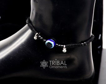 May include: Black ankle bracelet with a blue evil eye charm and silver beads. The bracelet is on a black mannequin leg. The text "TRIBAL Ornaments" is visible on the mannequin leg.