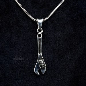 May include: A silver adjustable wrench pendant necklace. The wrench is detailed with a textured surface and a silver chain.