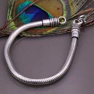 K&ouml;nnte beinhalten: Ein silbernes Schlangenkettenarmband mit einem Verschluss. Das Armband ist aus 925er Sterlingsilber.
