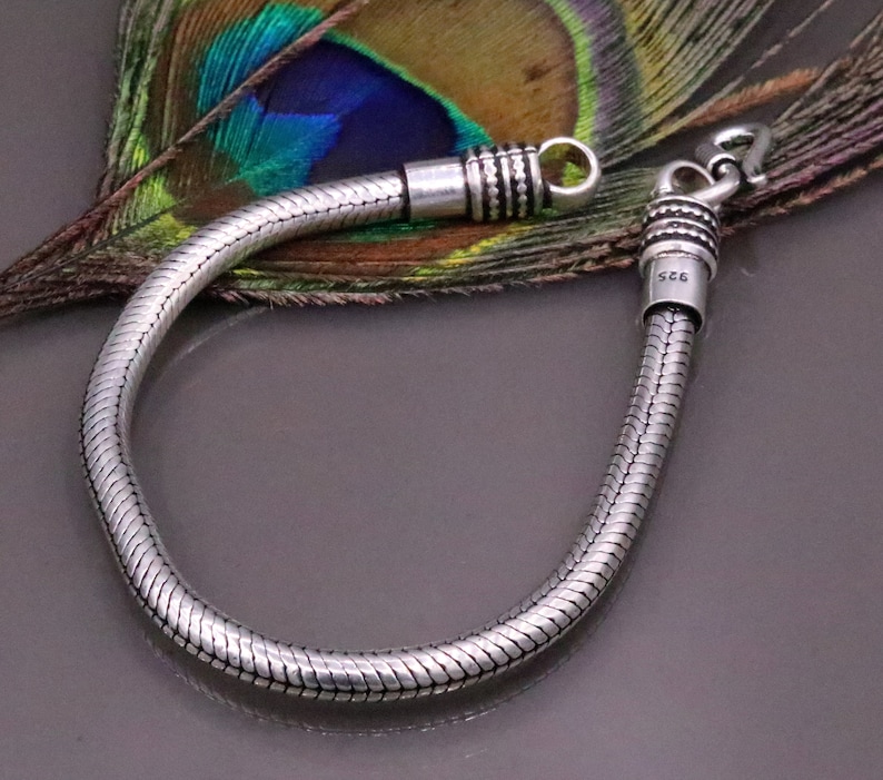 K&ouml;nnte beinhalten: Ein silbernes Schlangenkettenarmband mit einem Verschluss. Das Armband ist aus 925er Sterlingsilber.