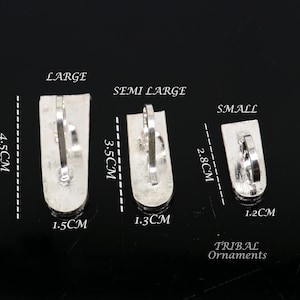 May include: Three silver nose rings in different sizes: large, semi-large, and small. The rings are 4.5 cm, 3.5 cm, and 2.8 cm long, respectively. The rings are 1.5 cm, 1.3 cm, and 1.2 cm wide, respectively. The text "TRIBAL Ornaments" is printed below the rings.