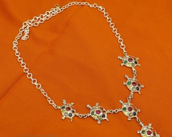 May include: A silver necklace with a chain and multiple turtle pendants. Each turtle is decorated with colorful gemstones.