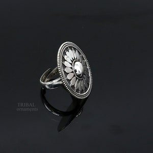 May include: A silver ring featuring a large, round, floral design. The ring is crafted from sterling silver and boasts a delicate, intricate design.