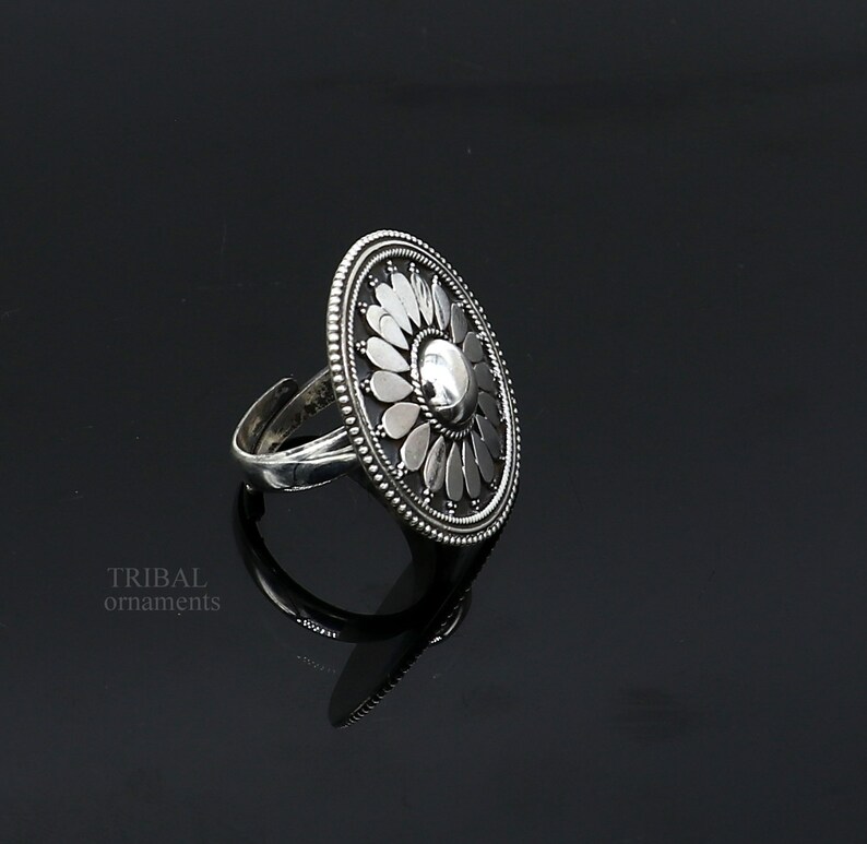 May include: A silver ring featuring a large, round, floral design. The ring is crafted from sterling silver and boasts a delicate, intricate design.