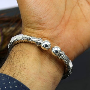 Op de afbeelding: Een zilveren armband met een getextureerd ontwerp en twee ronde balaccenten.