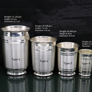 May include: Four silver drinking cups of varying sizes. The cups are all cylindrical with a rounded bottom and a lip at the top. Each cup has a silver band around the middle and a brushed silver finish. The cups are labeled "Type-1", "Type-2", "Type-3", and "Type-4". The text below each cup indicates the weight, height, and diameter of each cup in centimeters and grams.