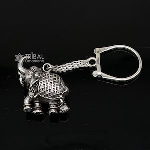May include: Silver elephant keychain with a detailed design and a silver chain attached to a silver ring.