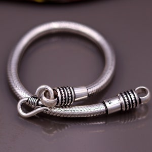 K&ouml;nnte beinhalten: Ein silbernes Schlangenkettenarmband mit strukturiertem Design und einem Verschluss.