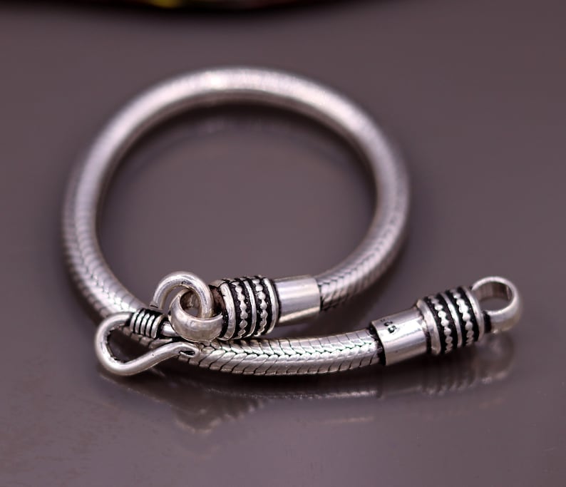 K&ouml;nnte beinhalten: Ein silbernes Schlangenkettenarmband mit strukturiertem Design und einem Verschluss.