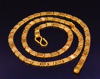 May include: A gold chain necklace with a square link design. The chain is made of textured metal and has a polished finish.