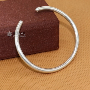 May include: A silver bangle bracelet with a smooth, rounded surface. The bracelet is simple and elegant, and it would make a great gift for any occasion.