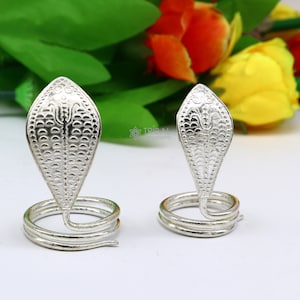 May include: Two silver snake-shaped rings with a textured design. The rings are on a white surface.