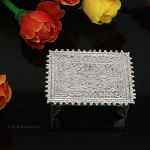 Puede incluir: Una bandeja de plata con un intrincado diseño floral y un borde de cuentas. La bandeja está sobre una superficie negra.