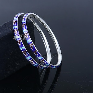 May include: Two silver bangles with blue and maroon enamel floral designs.