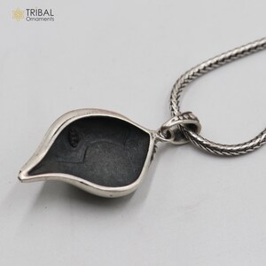 Op de afbeelding: Zilveren ketting met een hanger in de vorm van een blad. De achterkant van de hanger is glad en heeft een kleine lus om aan een ketting te bevestigen.