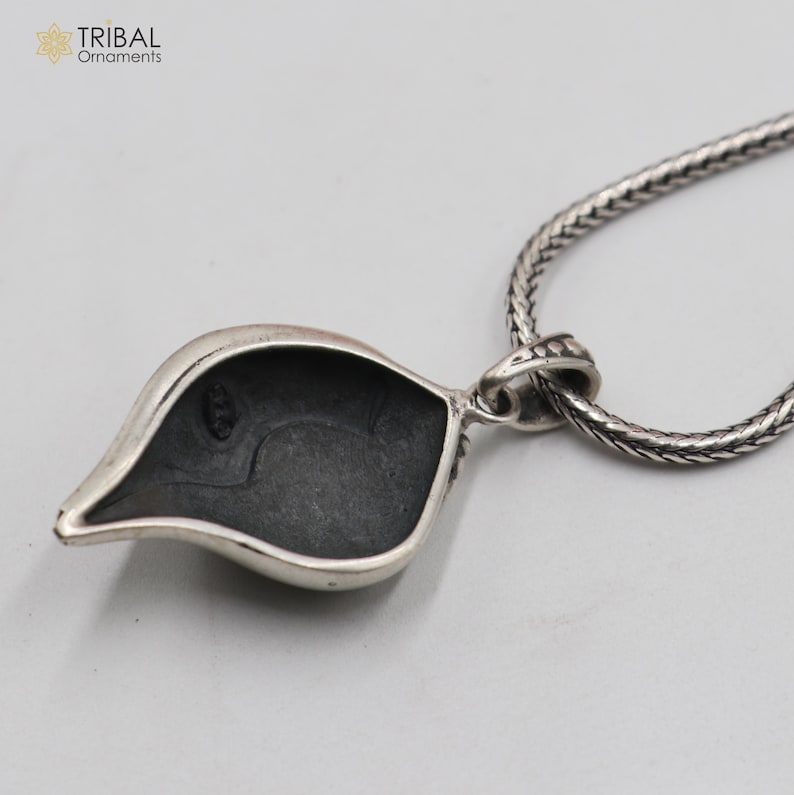 Op de afbeelding: Zilveren ketting met een hanger in de vorm van een blad. De achterkant van de hanger is glad en heeft een kleine lus om aan een ketting te bevestigen.