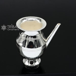 May include: A silver water pot with a spout and a round base. The pot is polished and shiny.