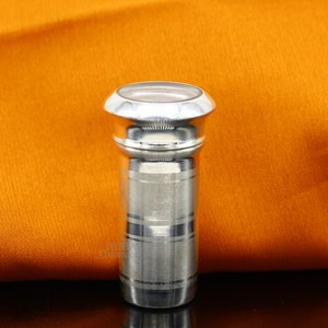 May include: Silver metal bottle stopper with a round top and a ribbed body. The stopper has a shiny finish.