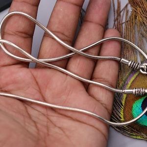 May include: A silver snake chain necklace with a clasp. The chain is thin and delicate, and the clasp is a simple hook.