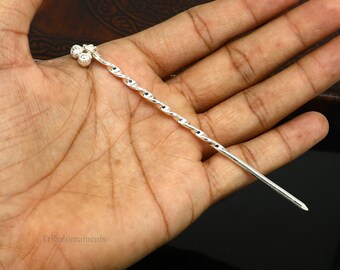 May include: Silver hair stick with a twisted design and a cluster of three round balls at the top.