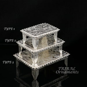 Puede incluir: Tres bandejas de plata escalonadas con intrincados diseños florales y bordes con cuentas. Las bandejas están apiladas una encima de la otra, con la bandeja más grande en la parte inferior y la bandeja más pequeña en la parte superior. Las bandejas están etiquetadas como "TYPE-1", "TYPE-2" y "TYPE-3". El texto "TRIBAL Ornaments" es visible en la parte inferior de la imagen.