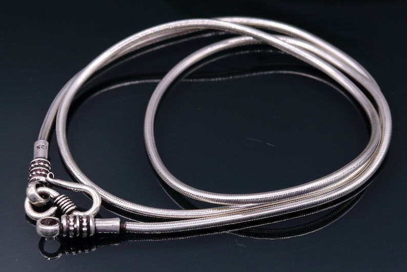 May include: A silver chain necklace with a hook clasp. The chain is made of a thin, round wire and has a smooth, polished finish.