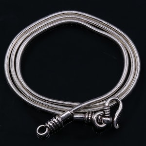 May include: A silver snake chain necklace with a silver clasp. The chain is made of multiple strands of silver wire that are twisted together.