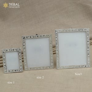 May include: Three silver picture frames with ornate floral designs. The frames are arranged in order of size, with the smallest frame on the left and the largest frame on the right. The frames are labelled "size 1", "size 2", and "Size 3".