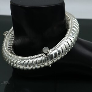 May include: A silver bangle bracelet with a textured design. The bracelet is open and has a hinged clasp.