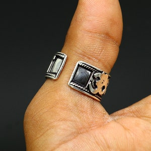 May include: Silver adjustable ring with an Om symbol design. The ring is open on one side and has a textured finish.